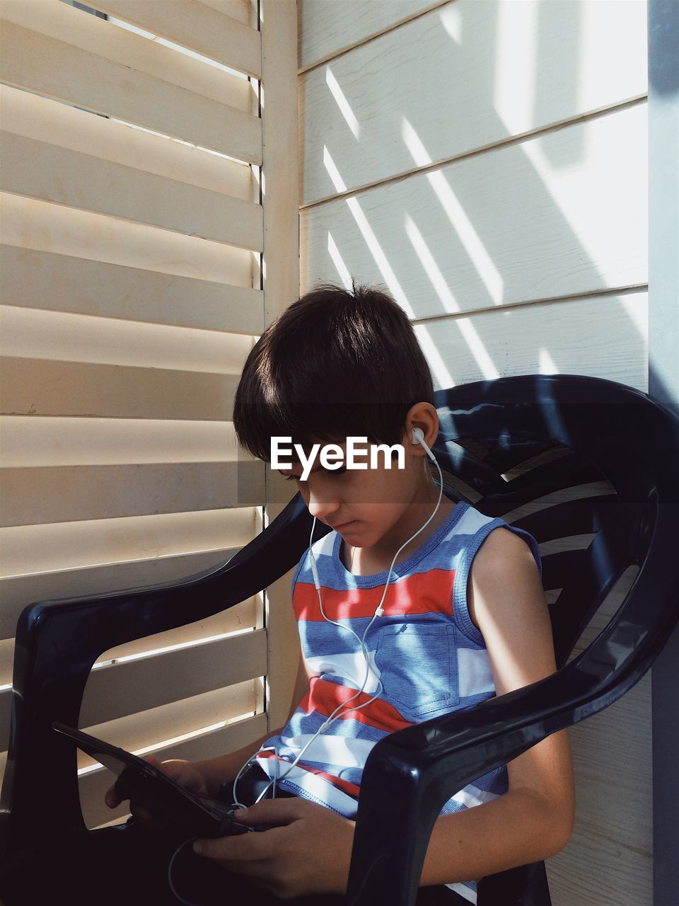 Boy using digital tablet while sitting on chair