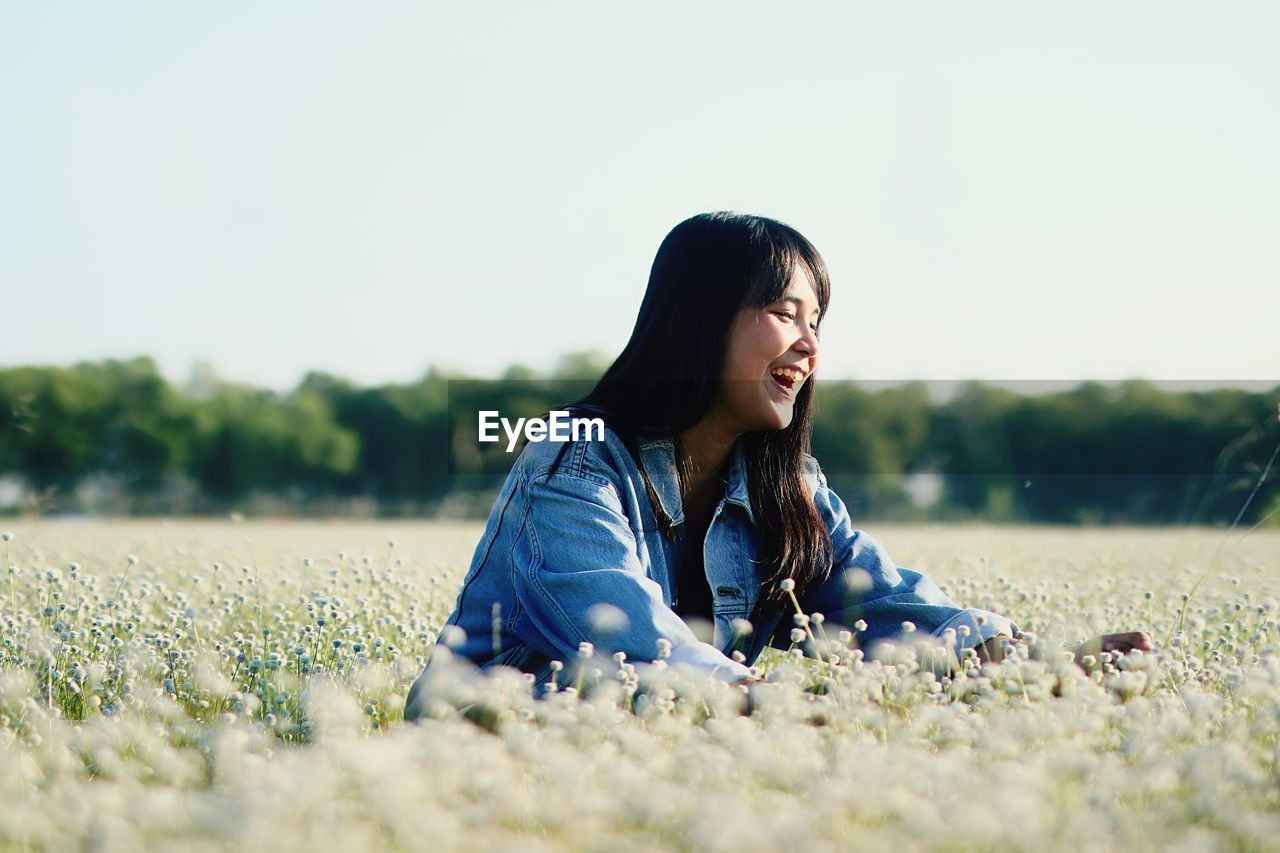 Smiling girl sitting by blooming flowers