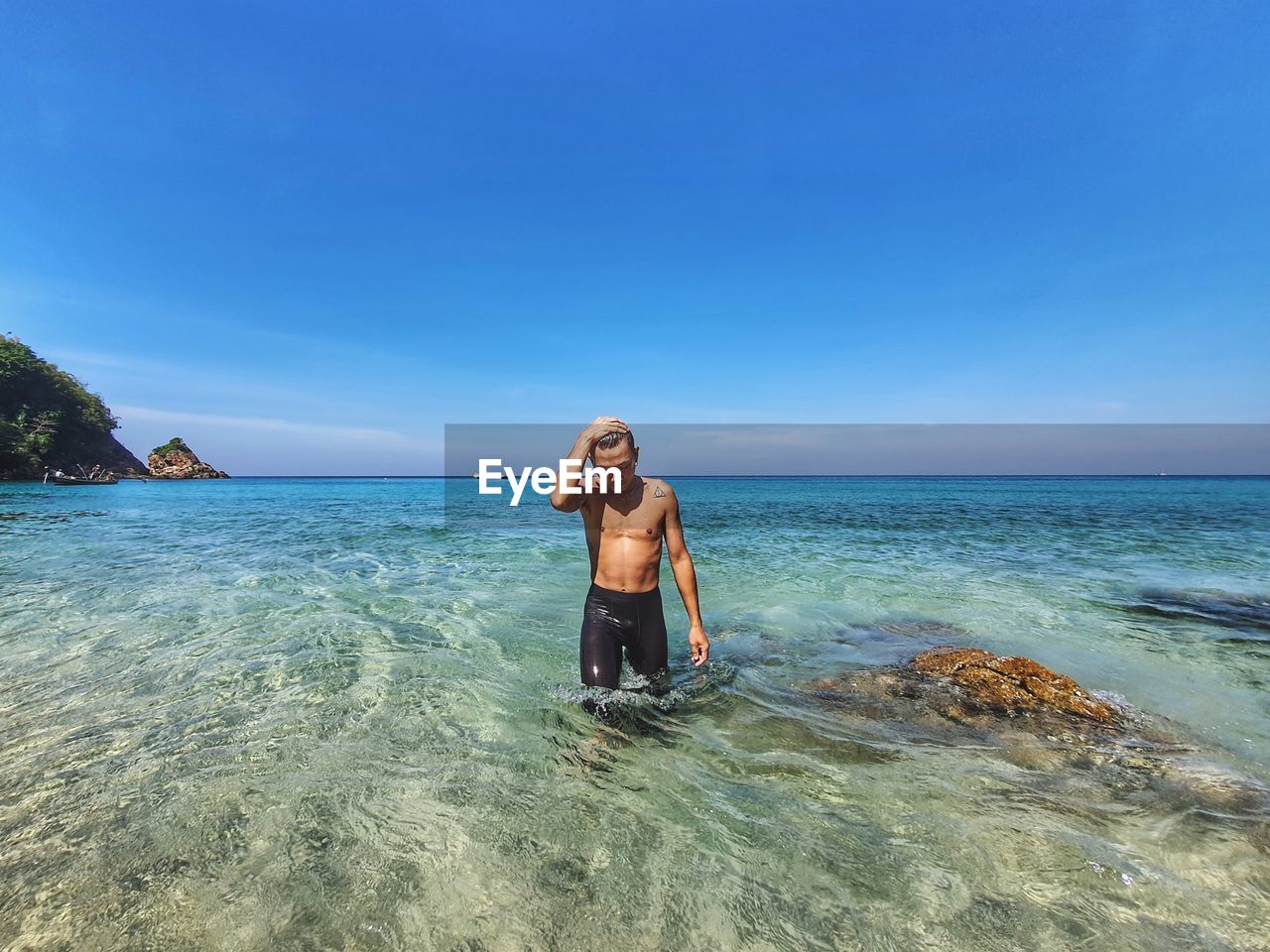 Shirtless man standing on seashore against sky