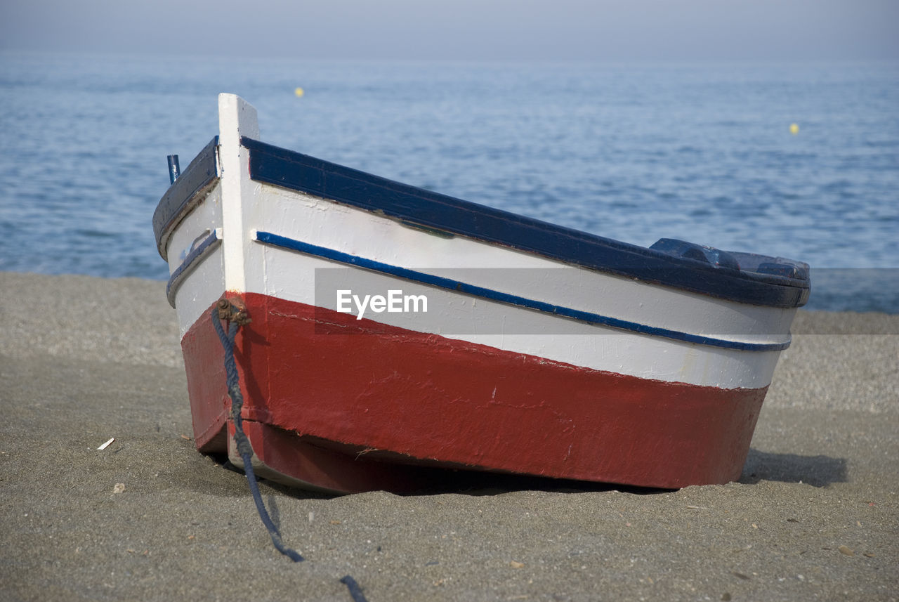 Empty multi colored small wooden rowing boat on beach
