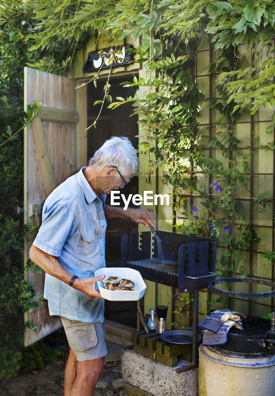 Elderly man roasts lamb chops in his garden