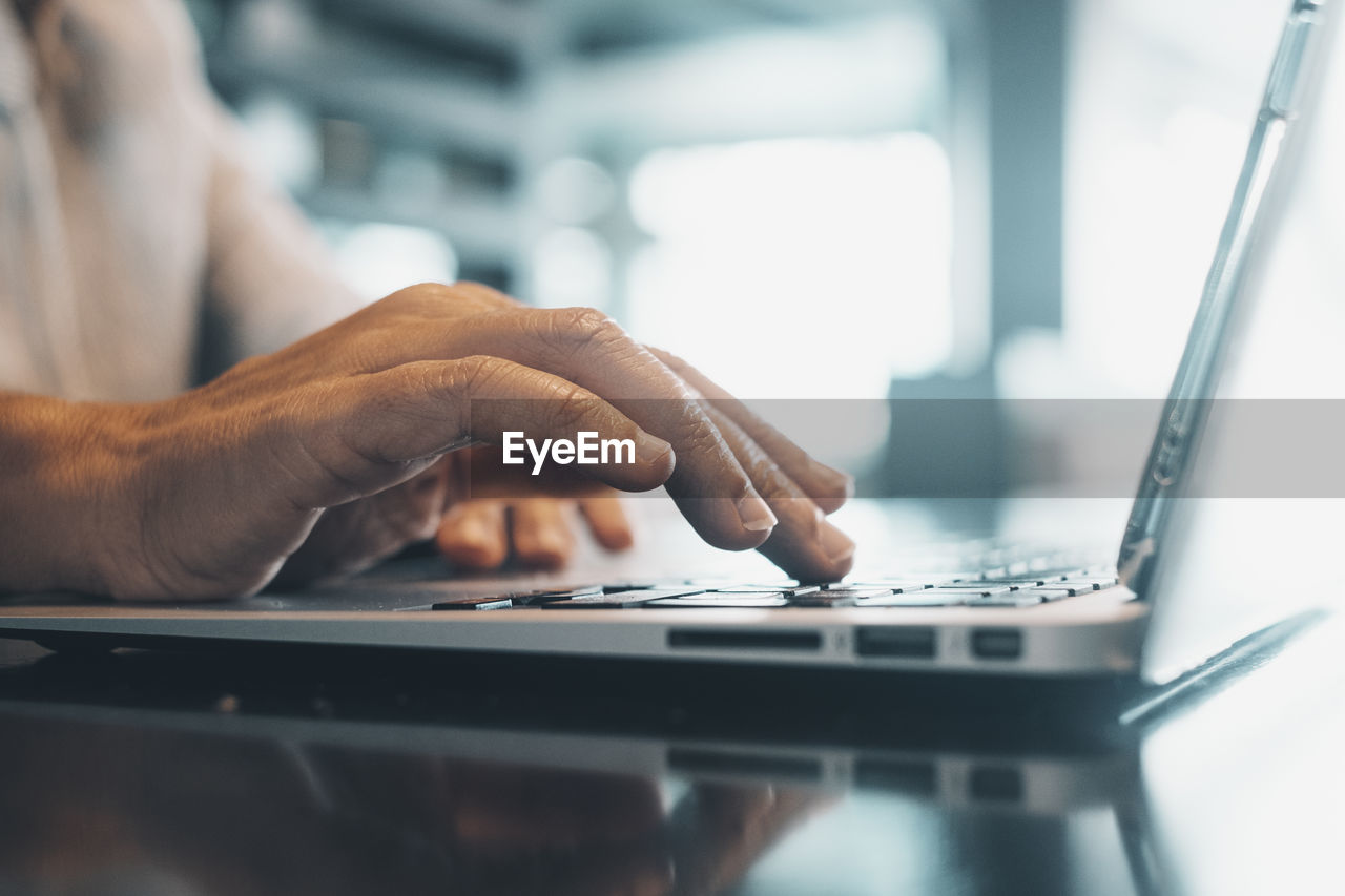 cropped hands of man using laptop