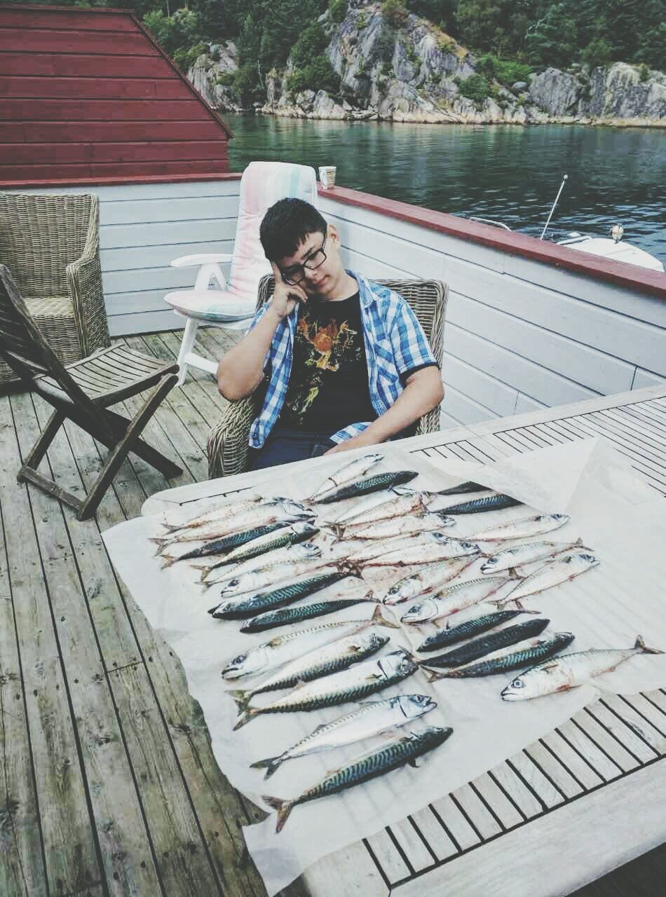 High angle view of boy sitting by fish at table in boat