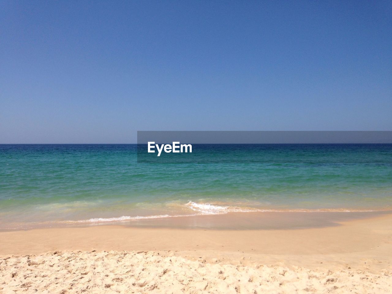 Scenic view of beach against clear blue sky