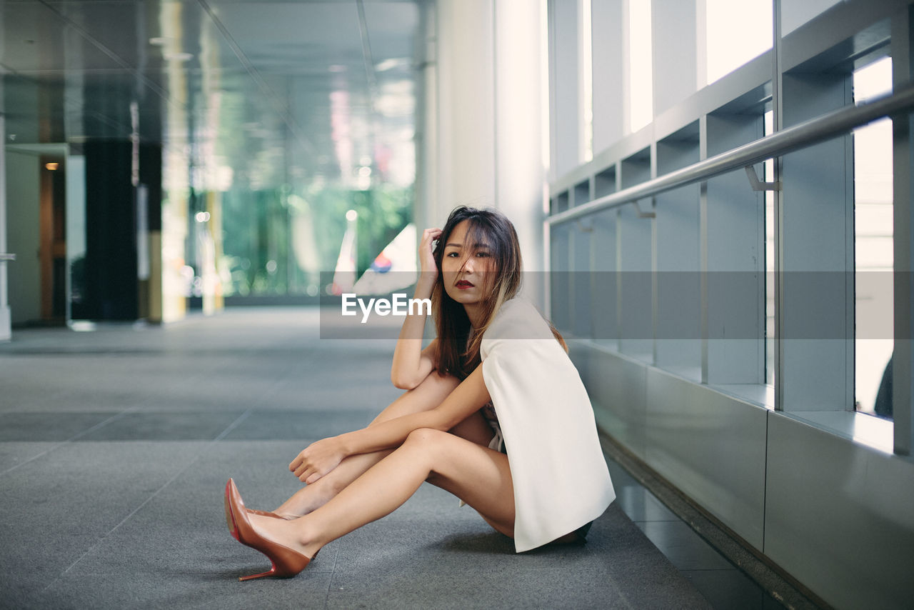 Portrait of young woman sitting by railing