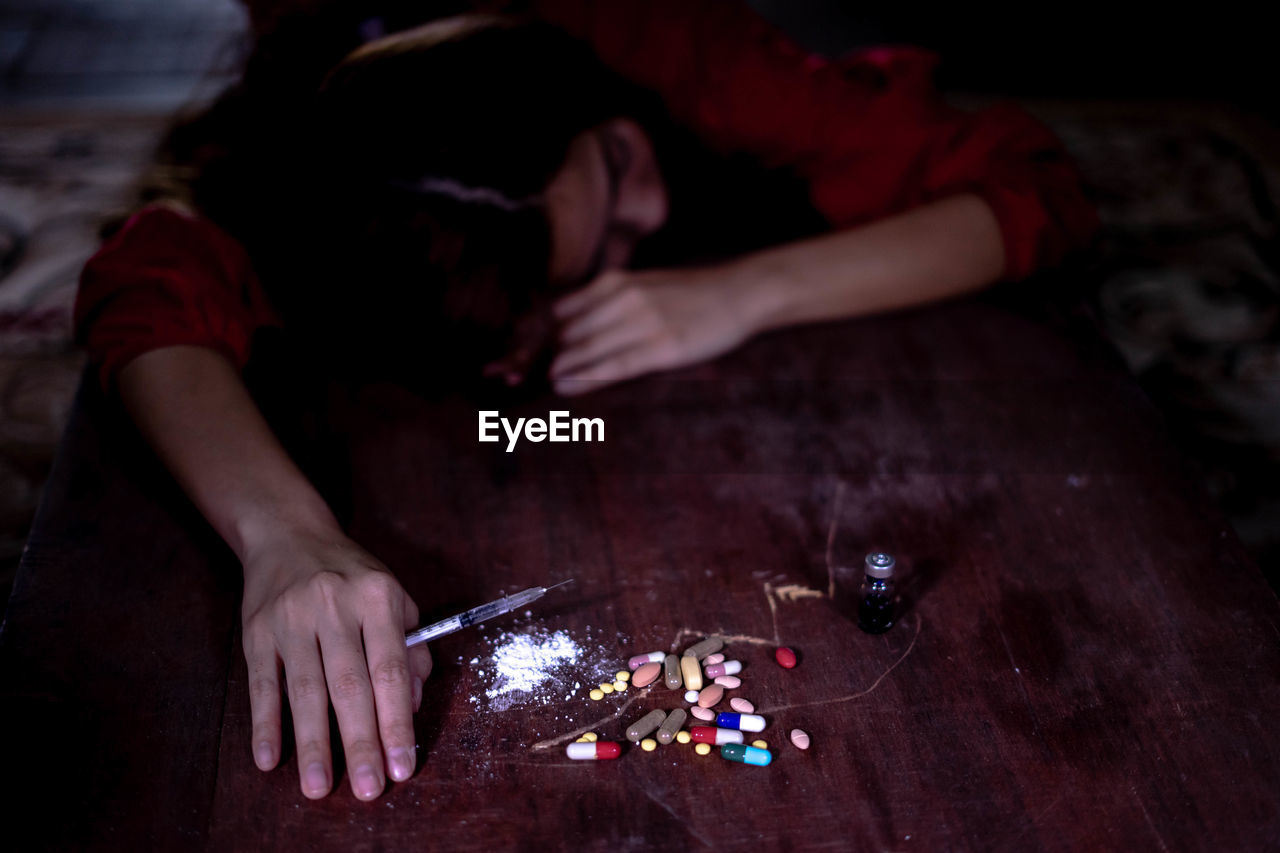 High angle view of woman suffering from drug overdose on table