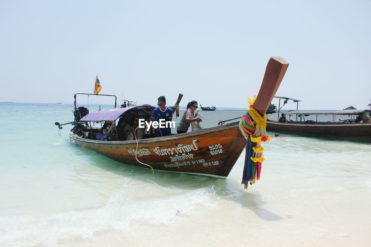 PEOPLE ON BOAT AT BEACH AGAINST SKY