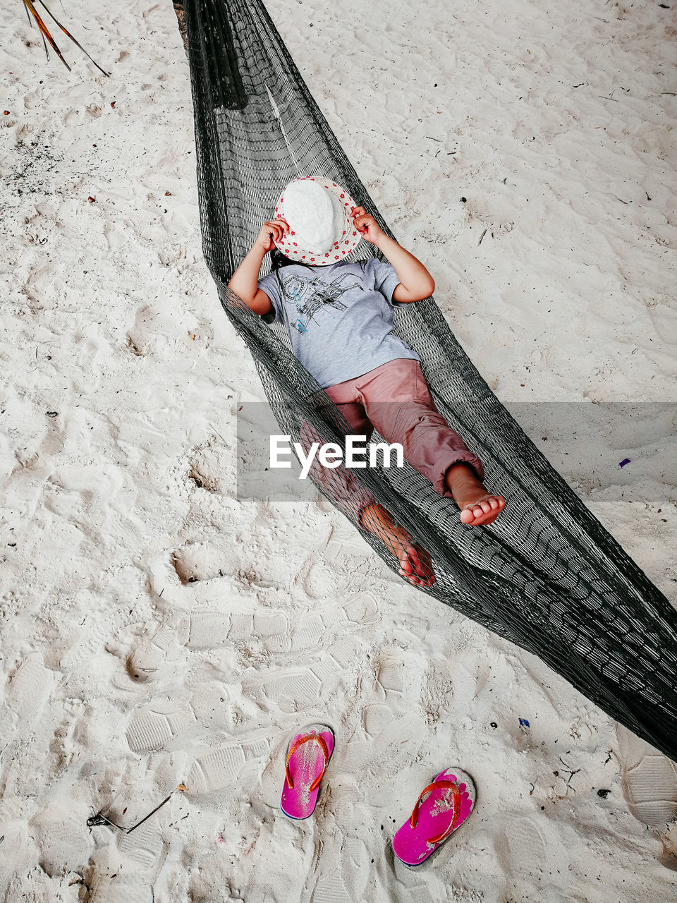 High angle view of woman lying in hammock at beach