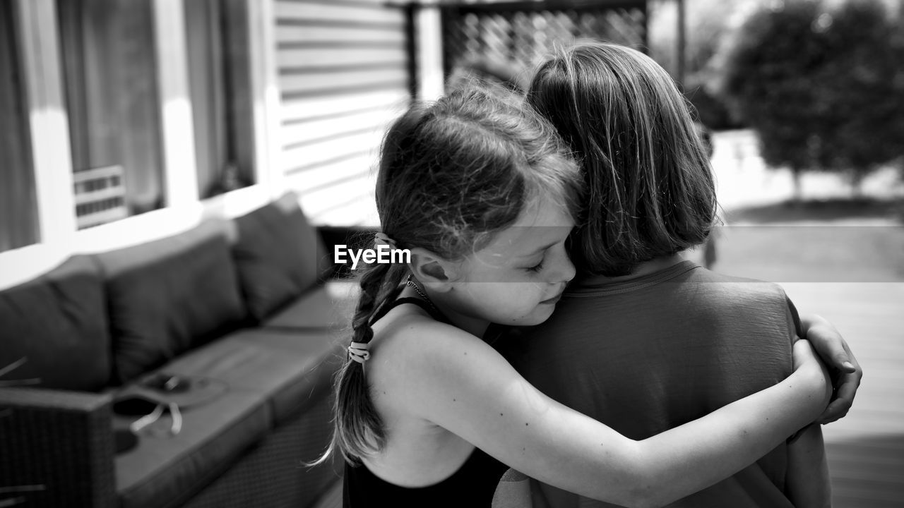 Side view of girl embracing sibling