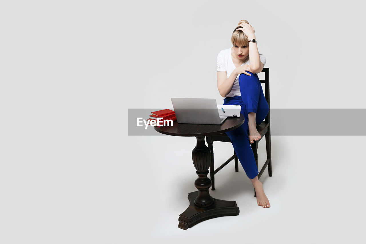 portrait of young woman using digital tablet while sitting on white background