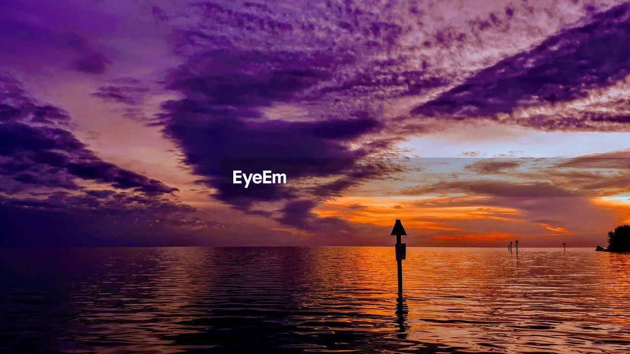 Scenic view of sea against dramatic sky during sunset