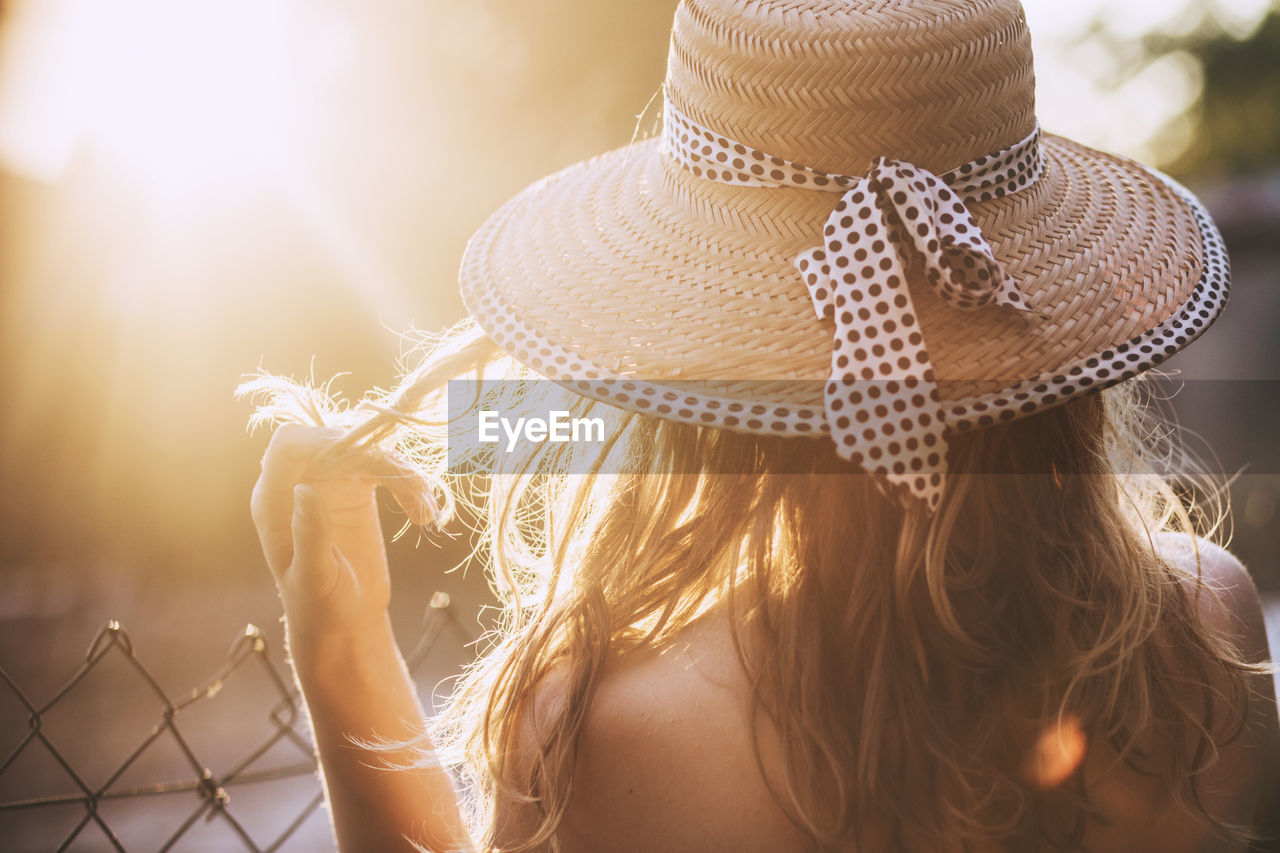 Back view of blond woman with straw hat on sunset