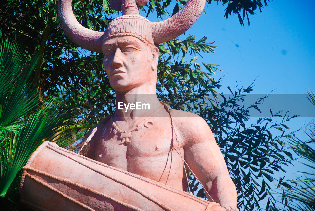 LOW ANGLE VIEW OF STATUE AGAINST TREE AND PLANTS