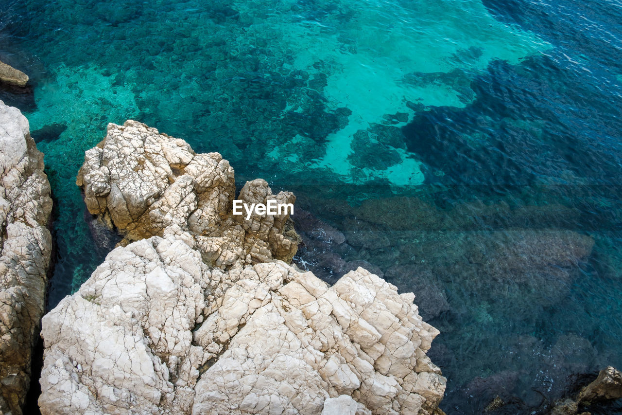 high angle view of rocks on sea