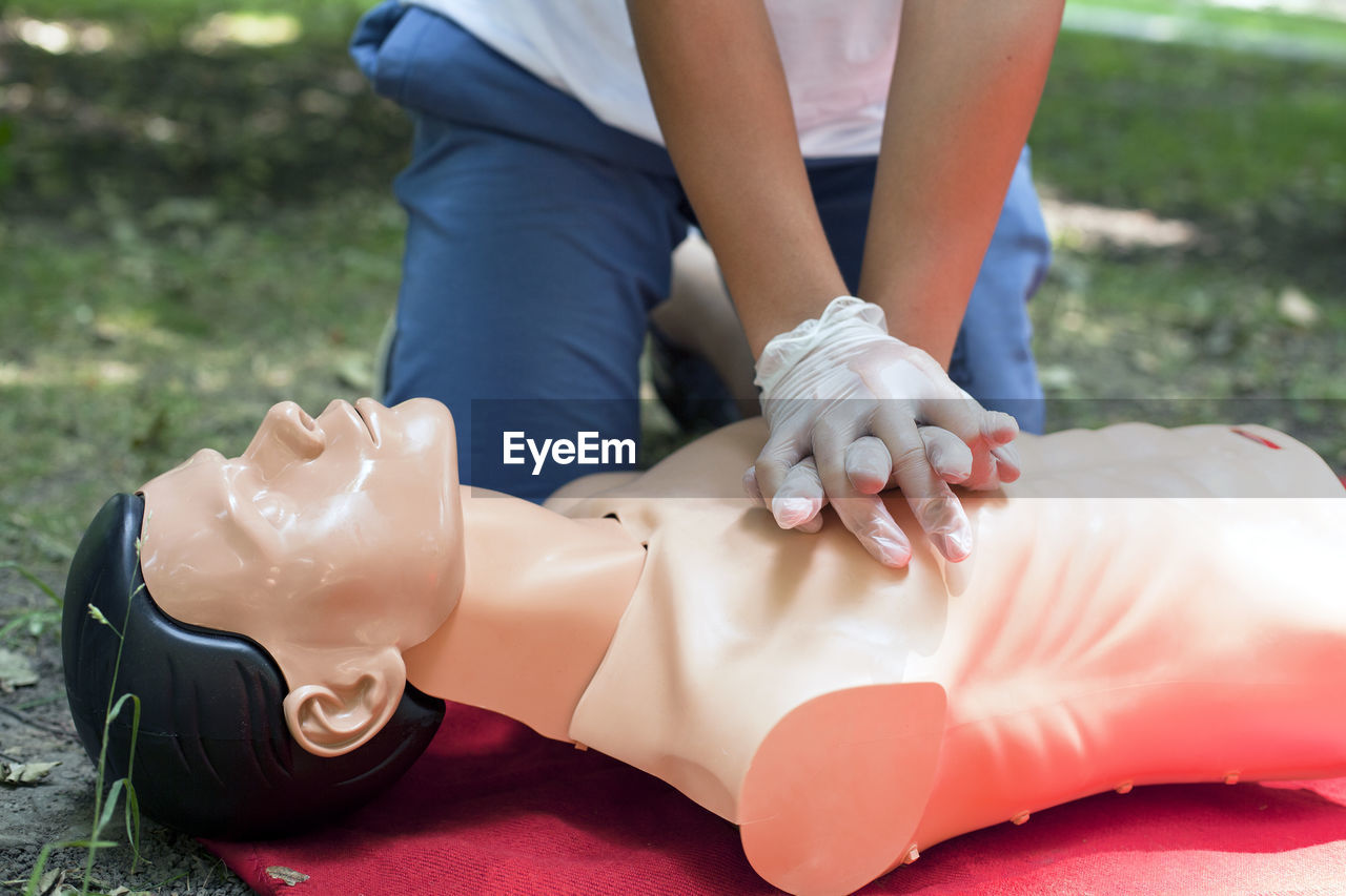 Low section of woman practicing cpr on dummy at field