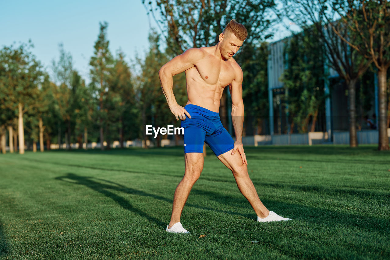 Full length of shirtless man with arms raised