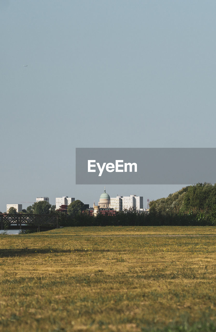 Buildings on field against clear sky