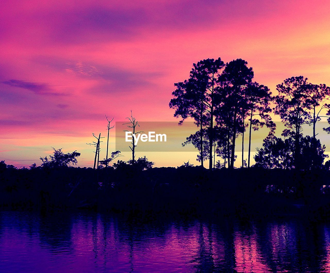 SILHOUETTE PALM TREES BY LAKE AGAINST SKY AT SUNSET