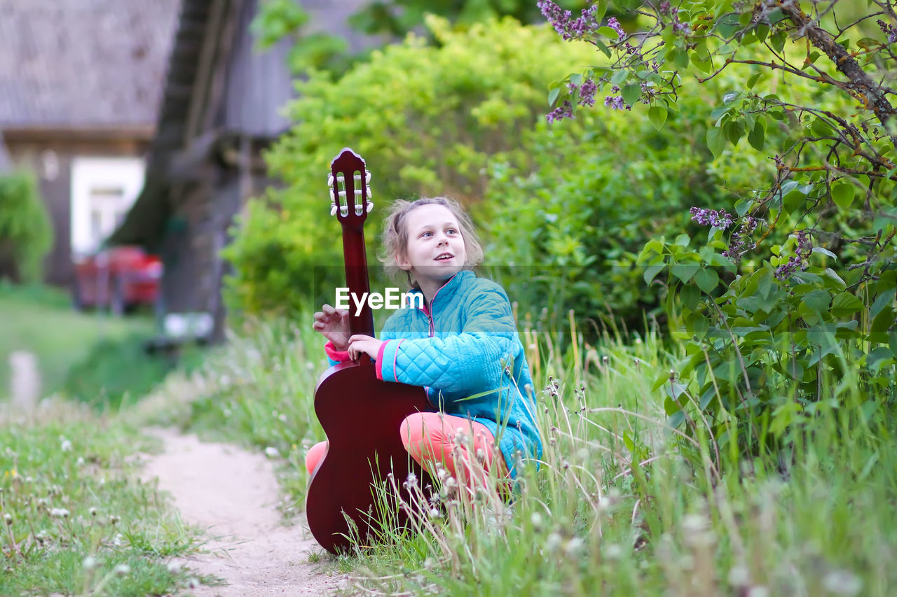 Cute girl playing guitar outdoors