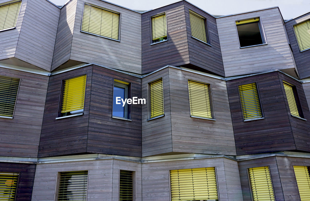 LOW ANGLE VIEW OF MODERN GLASS BUILDING IN CITY