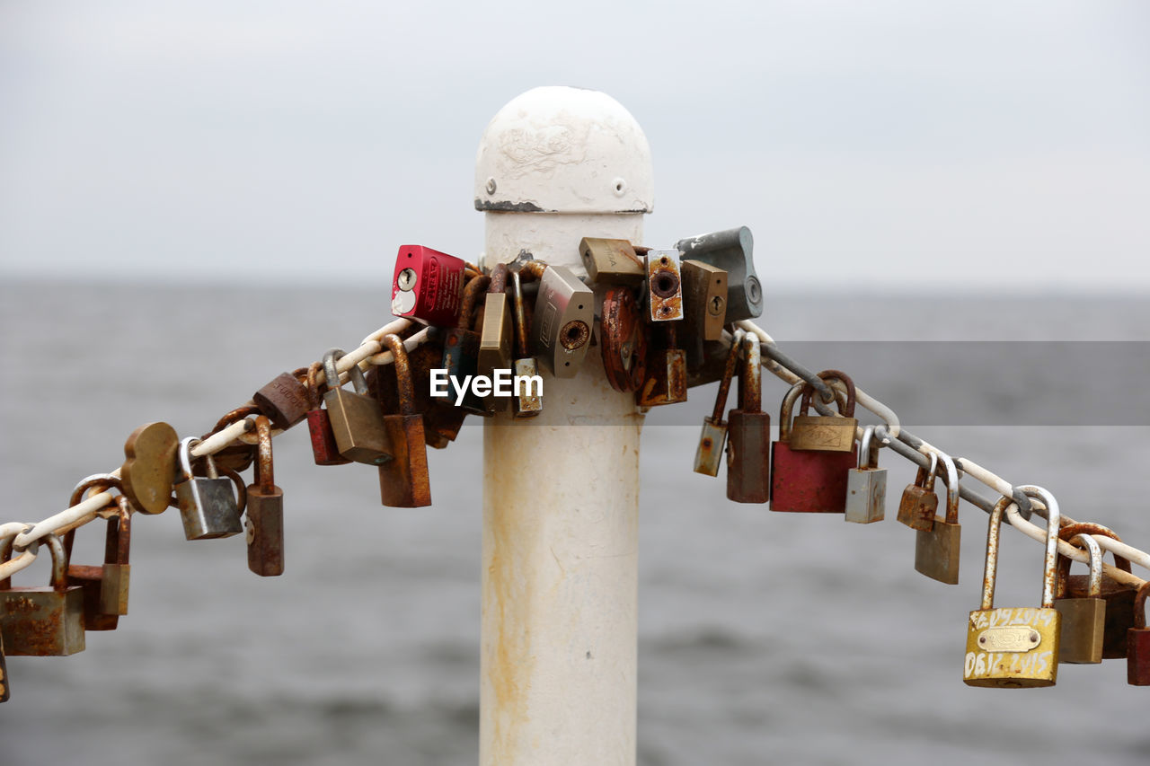 Close-up of padlocks on railing against sea