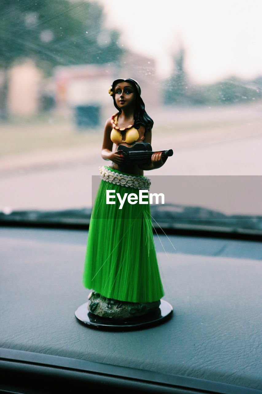 Close-up of female figurine on car dashboard