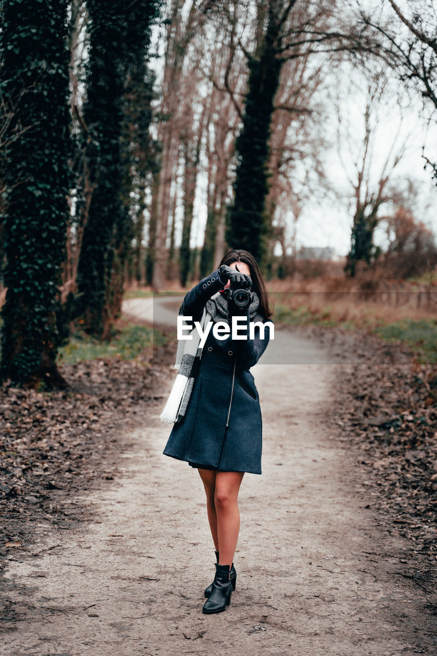 Full length of woman photographing in forest