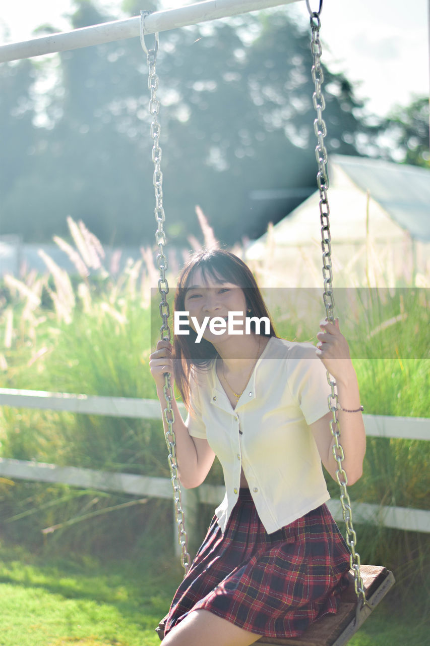 portrait of woman swinging at playground