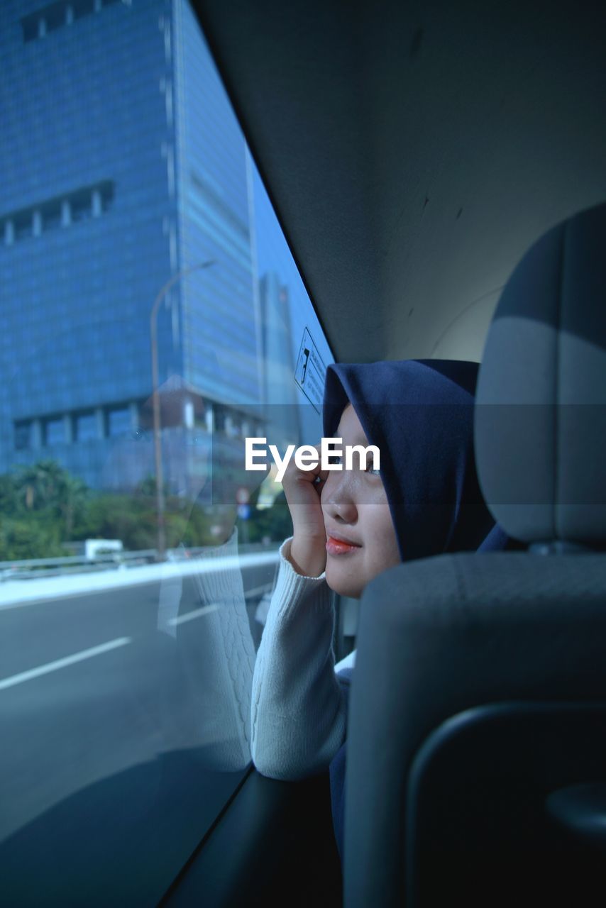 Close-up of teenage girl wearing hijab looking through window in car