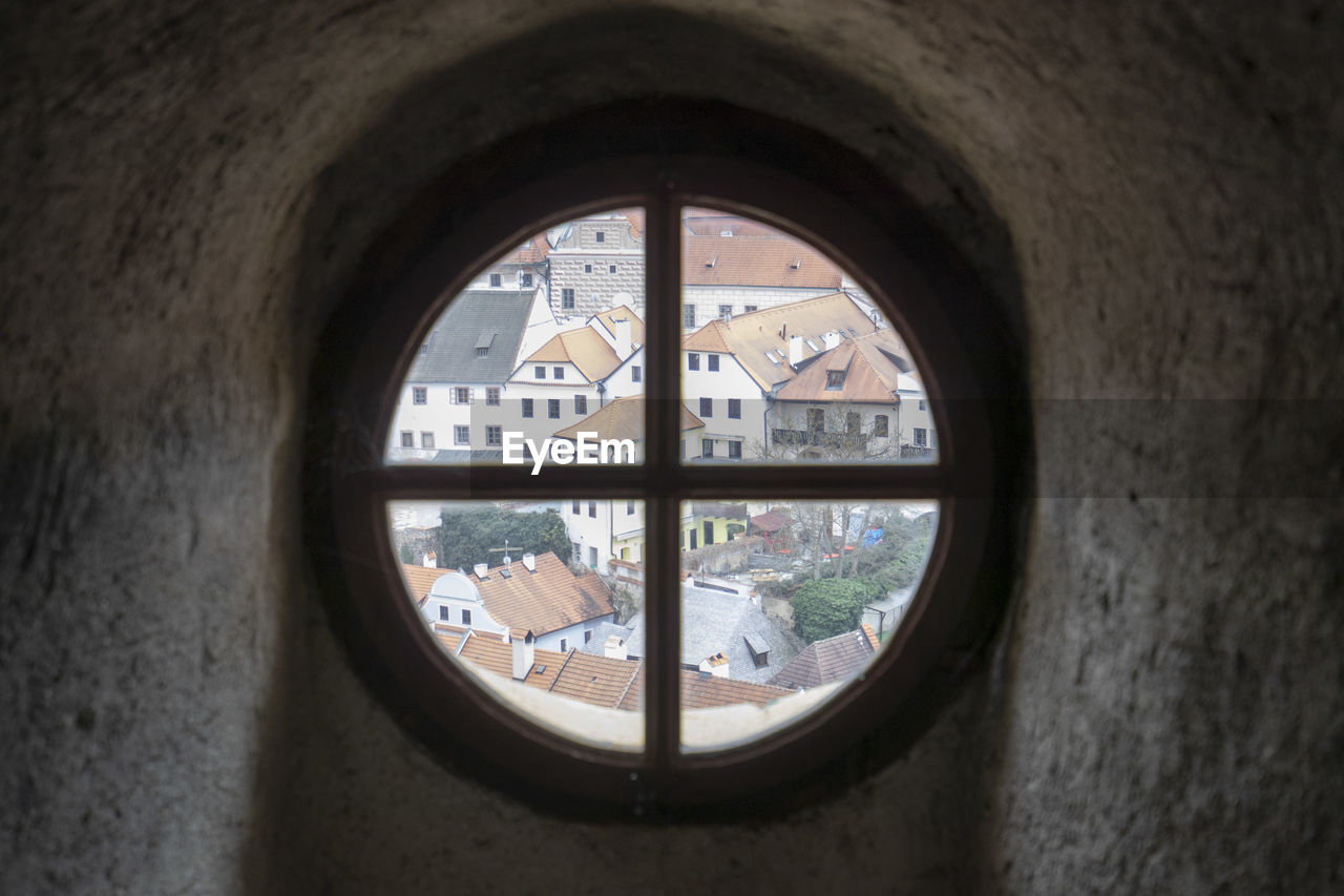 Townscape seen through circle glass window on wall
