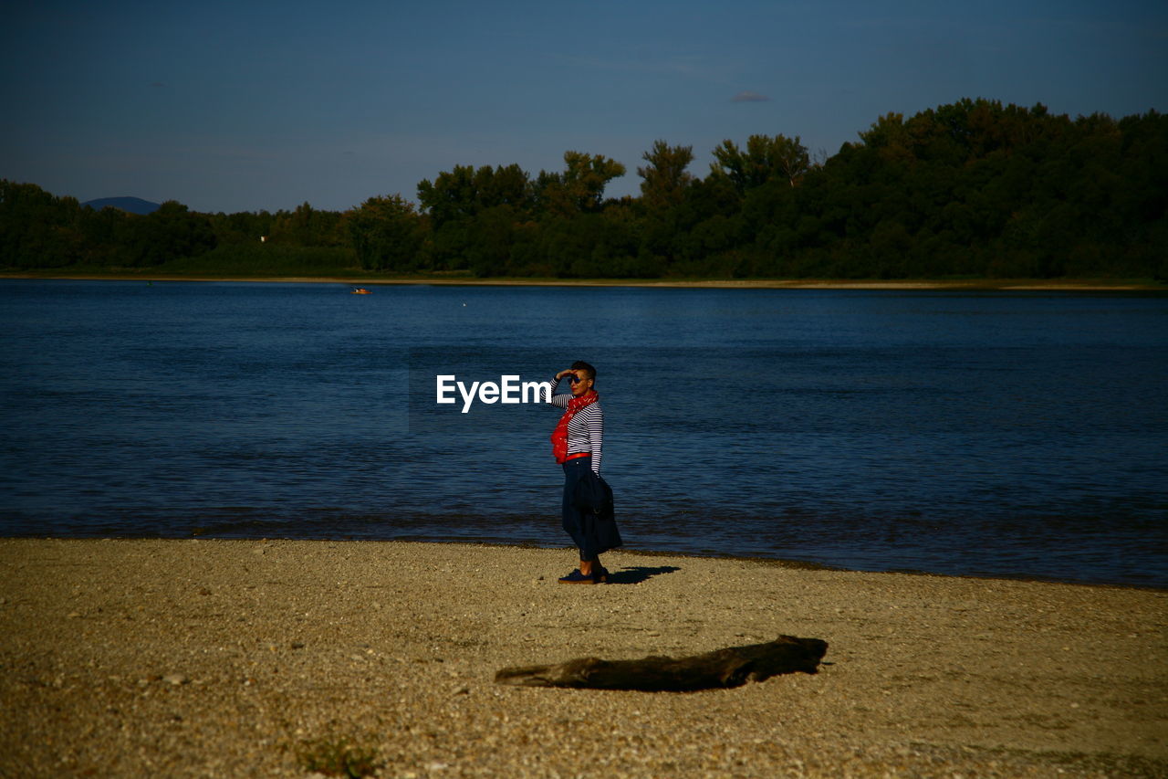 Woman wearing sunglasses while standing by lake 