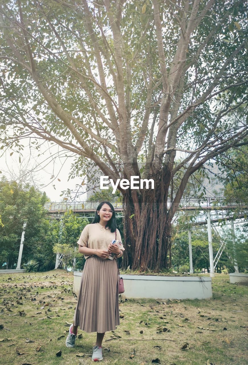 Full length of woman standing by tree