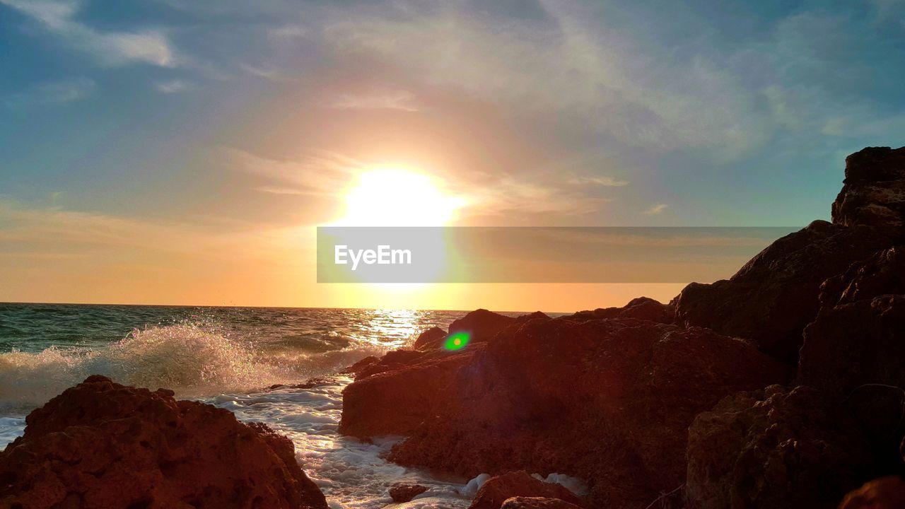 SCENIC VIEW OF BEACH AGAINST SKY AT SUNSET