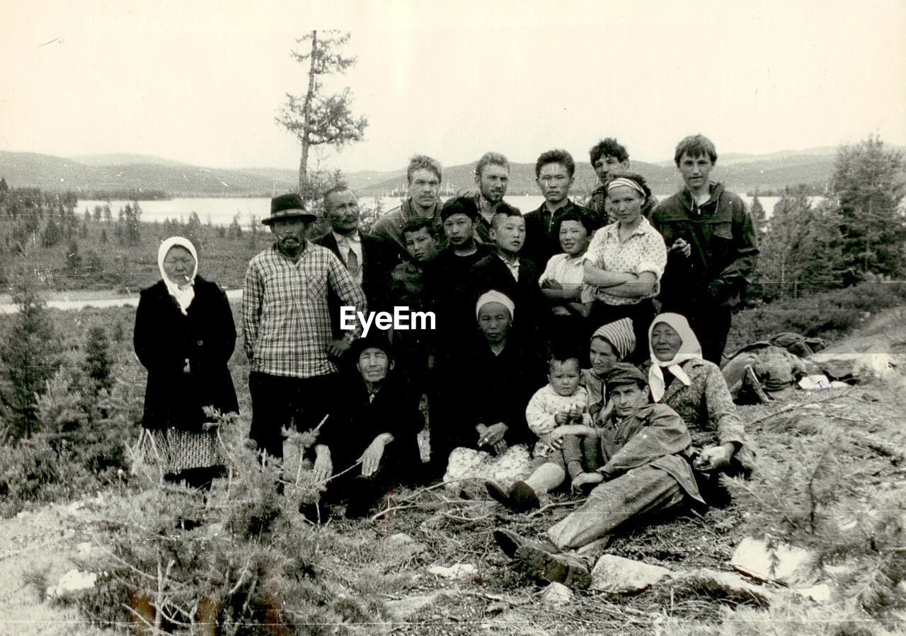 PEOPLE STANDING AGAINST TREES AND SKY