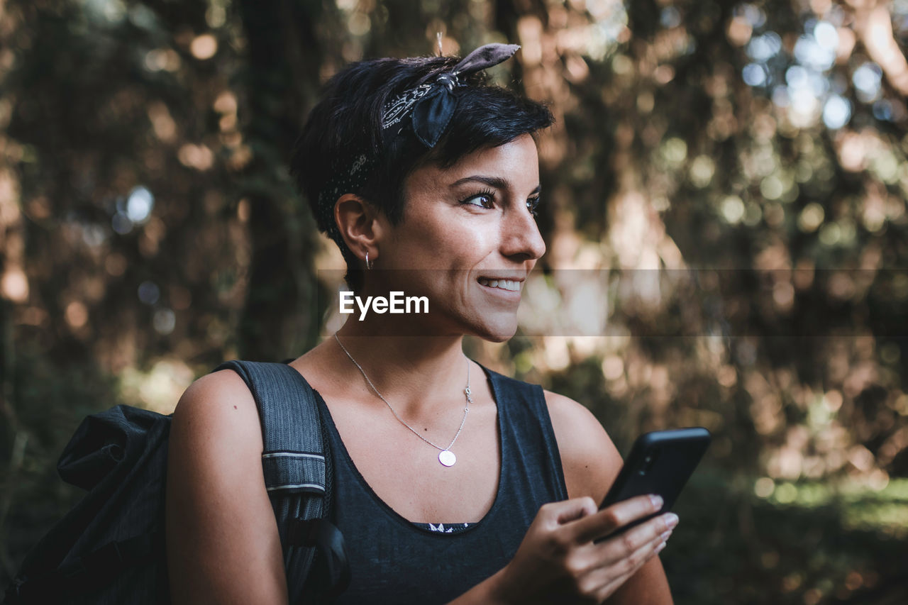 Portrait of smiling young woman using mobile phone outdoors