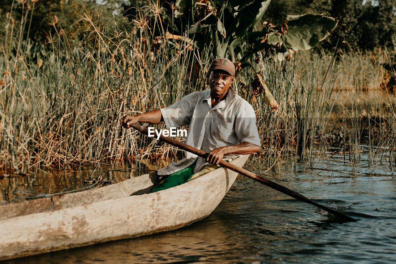 FULL LENGTH PORTRAIT OF A MAN HOLDING BOAT