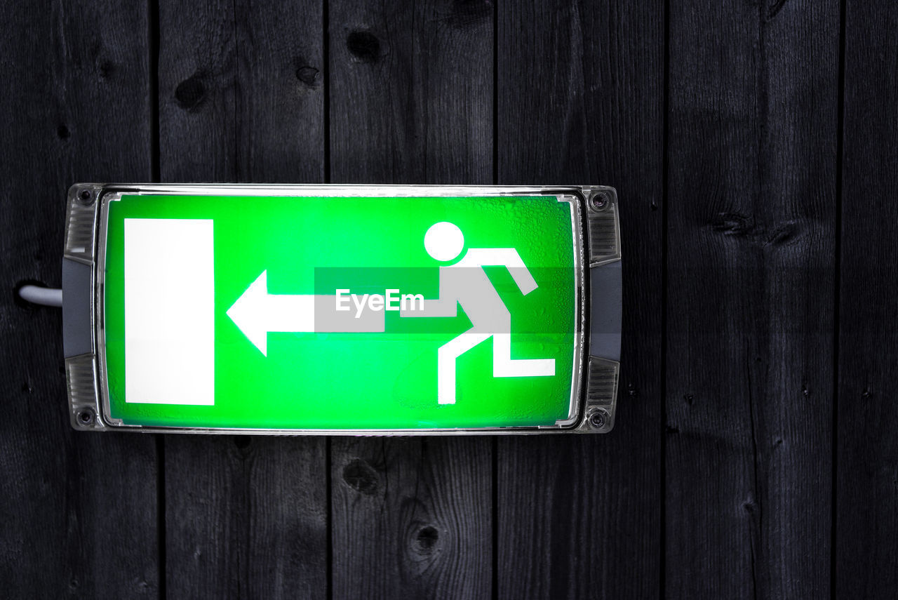 Close-up of illuminated directional sign on wooden door