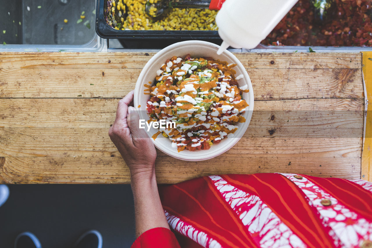 Midsection of female customer with fresh tex-mex in bowl at food truck