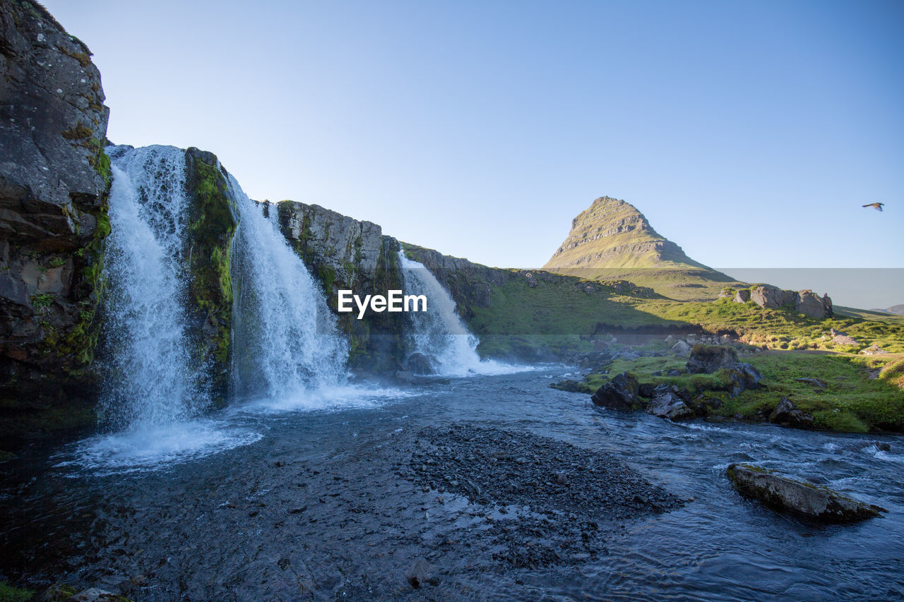 SCENIC VIEW OF WATERFALL AGAINST ROCKS