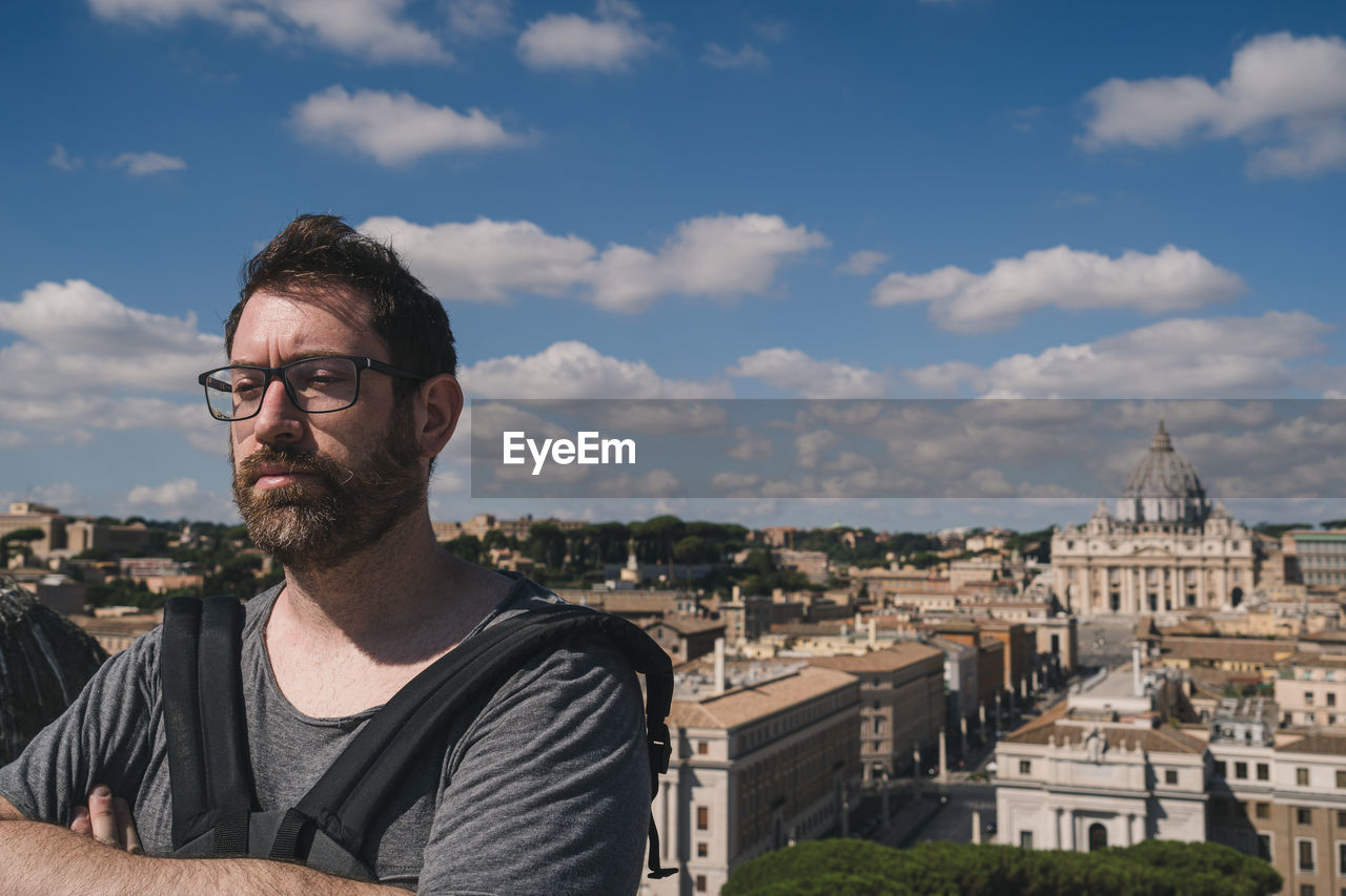 Portrait of mature man with cityscape against sky