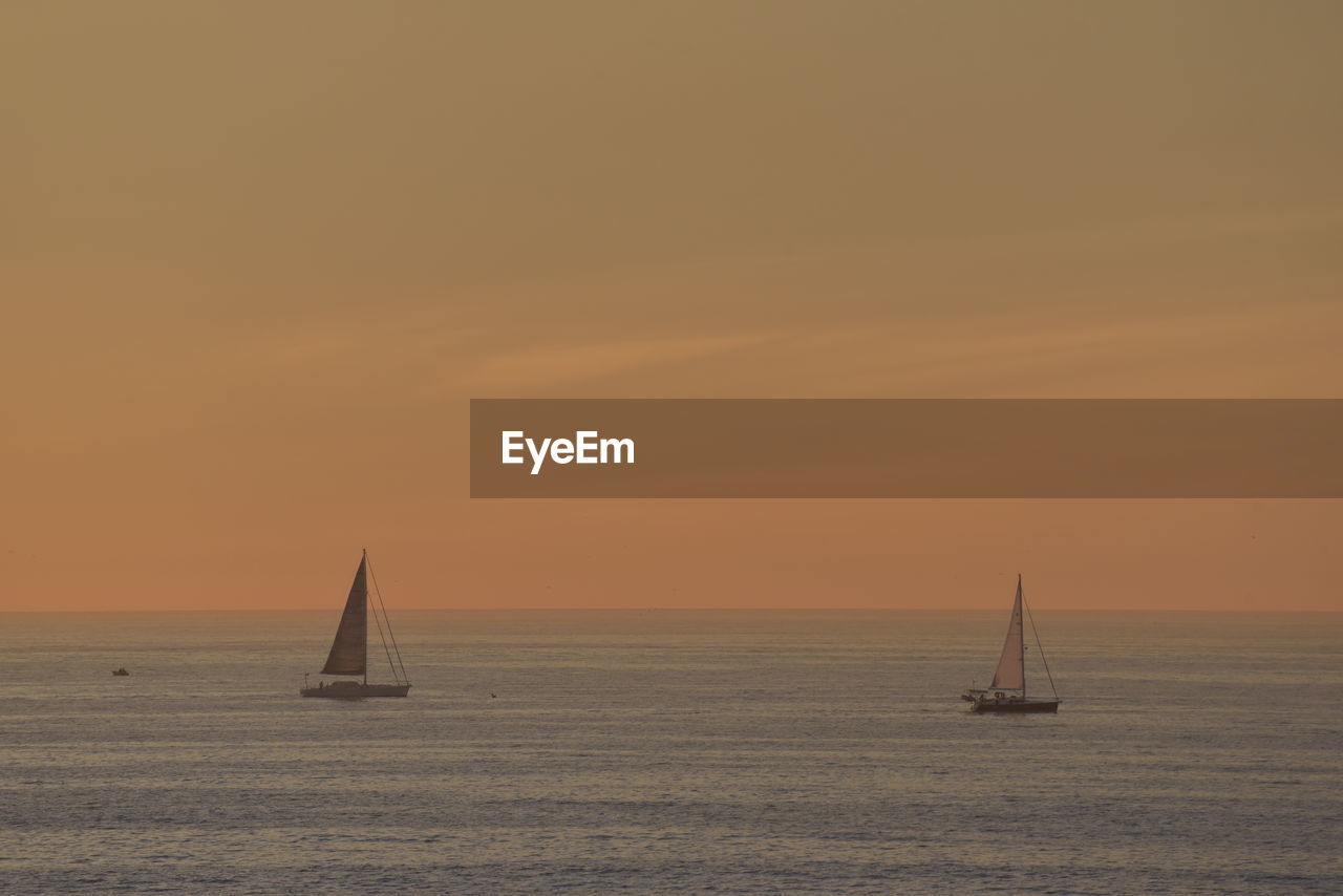 Sailboat sailing on sea against sky during sunset