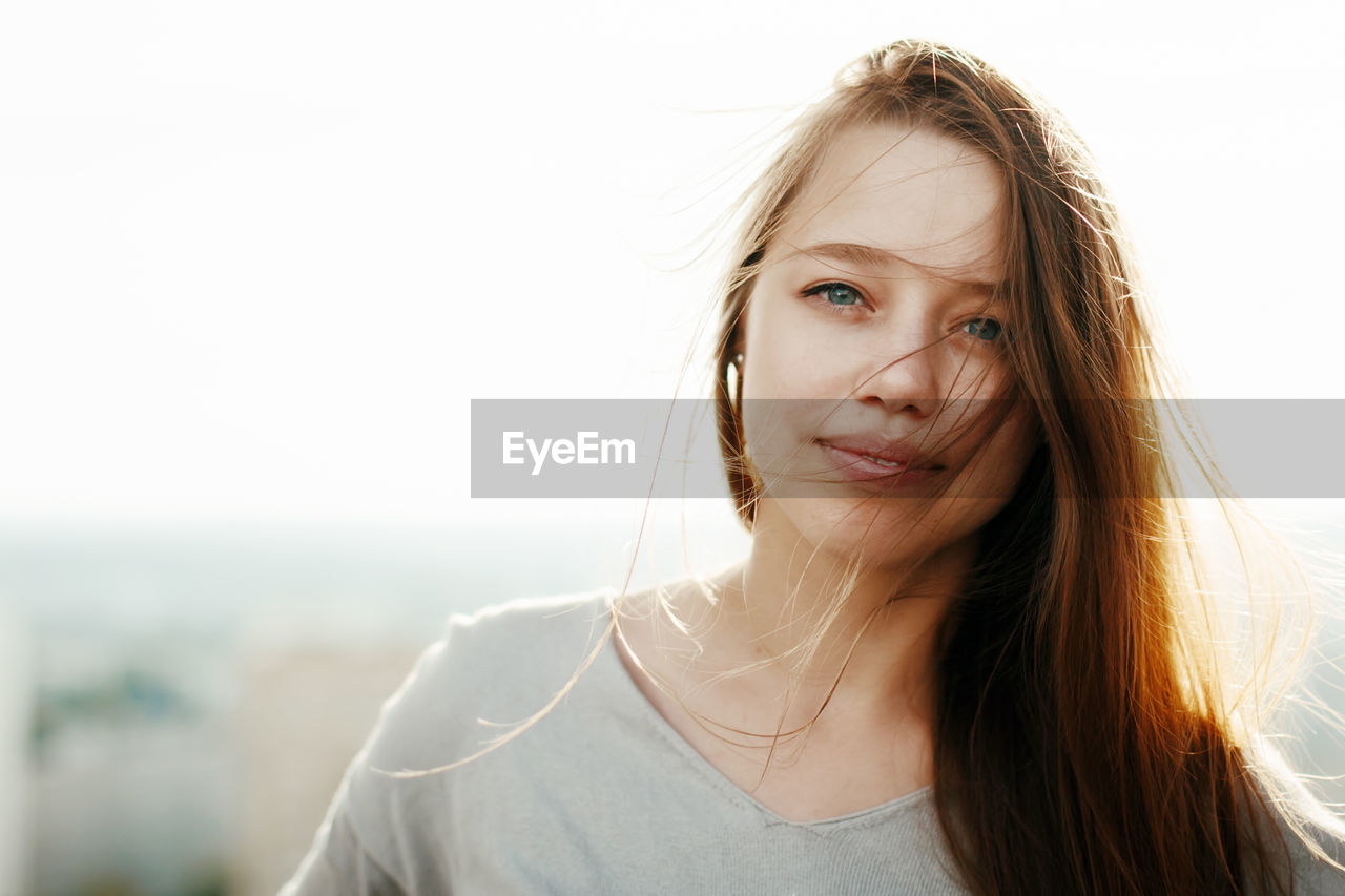 PORTRAIT OF YOUNG WOMAN AGAINST SKY