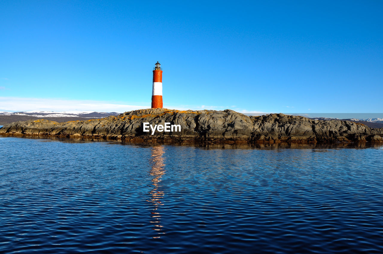 Scenic view of snowcapped mountains by beagle channel against orange sky