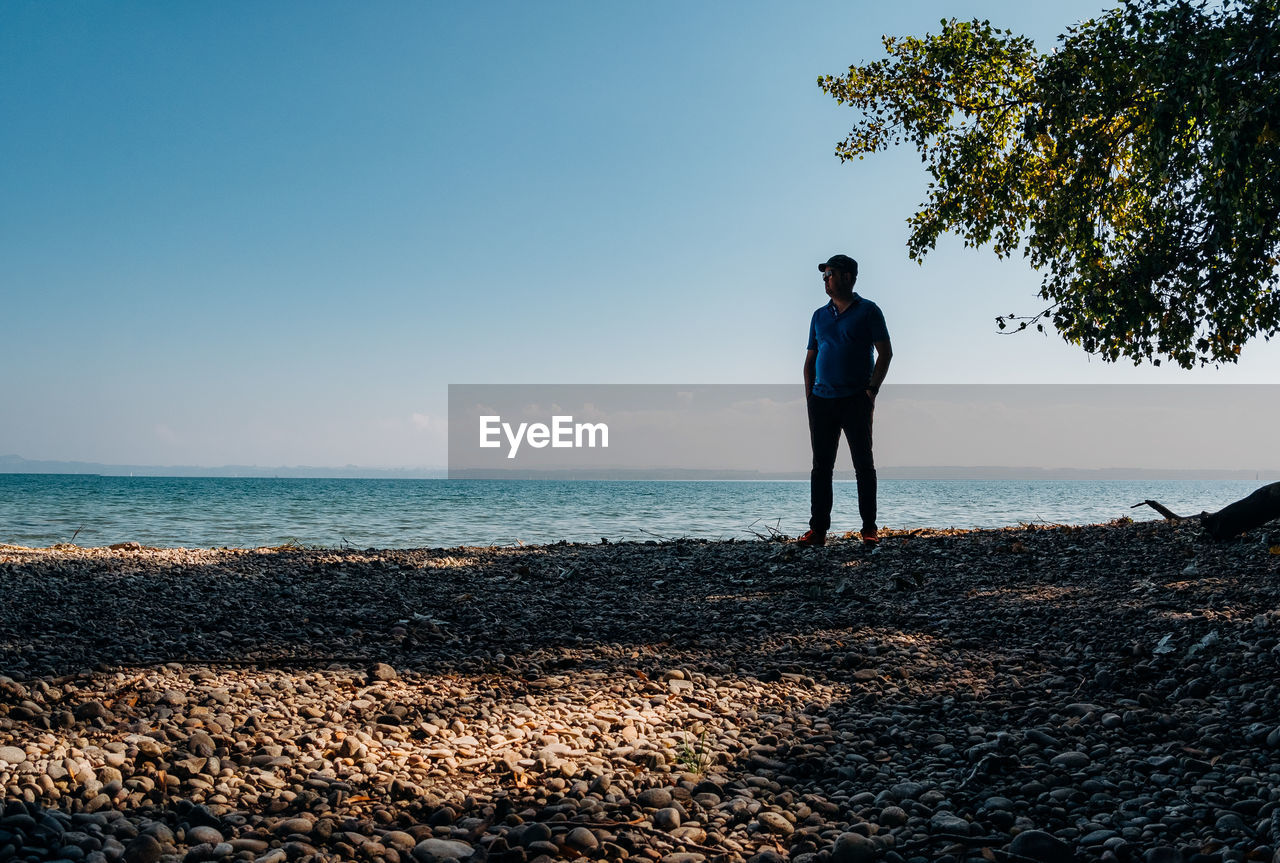 Full length of man standing on beach against sky