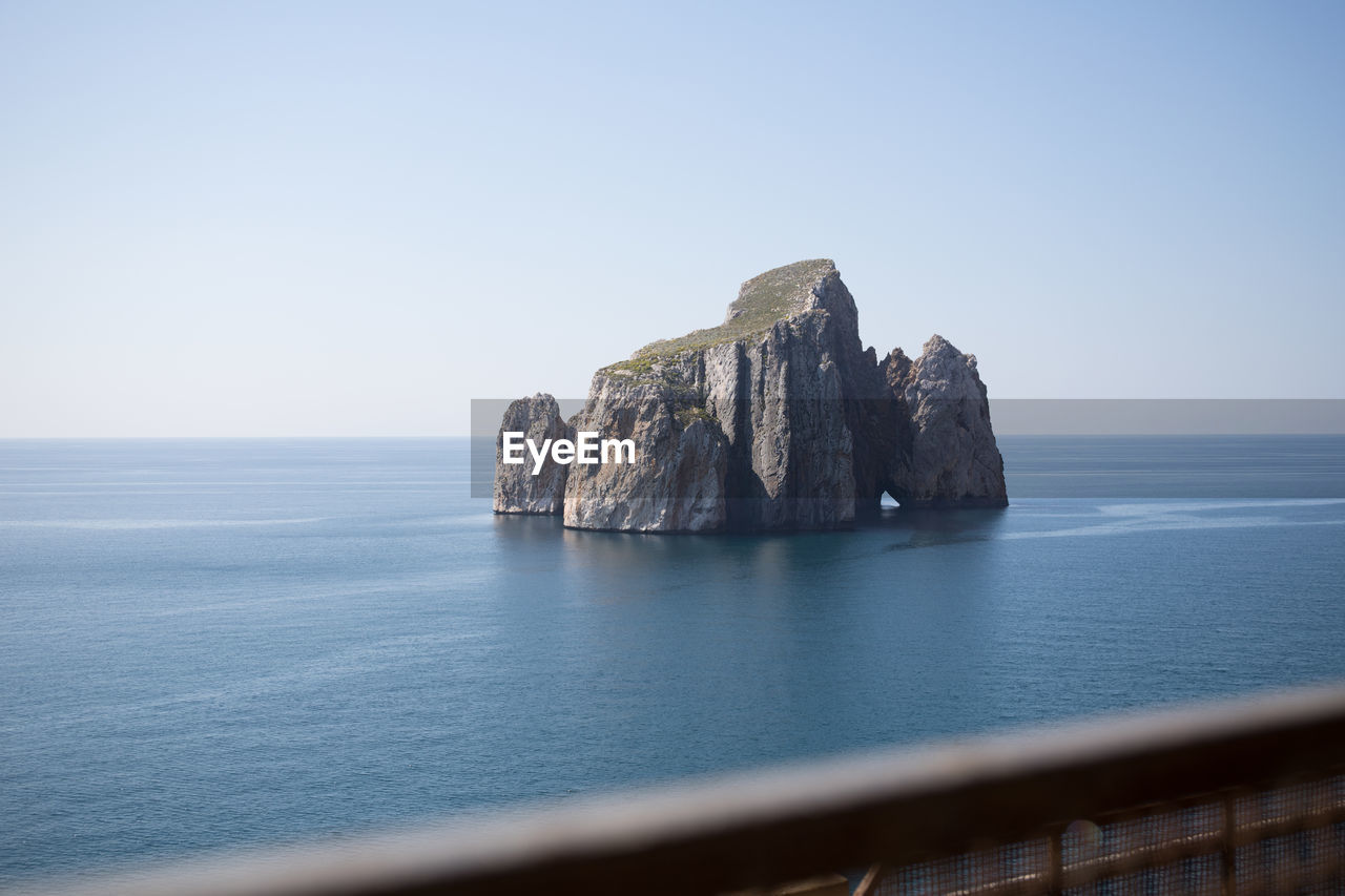 Rock formation in sea against clear sky