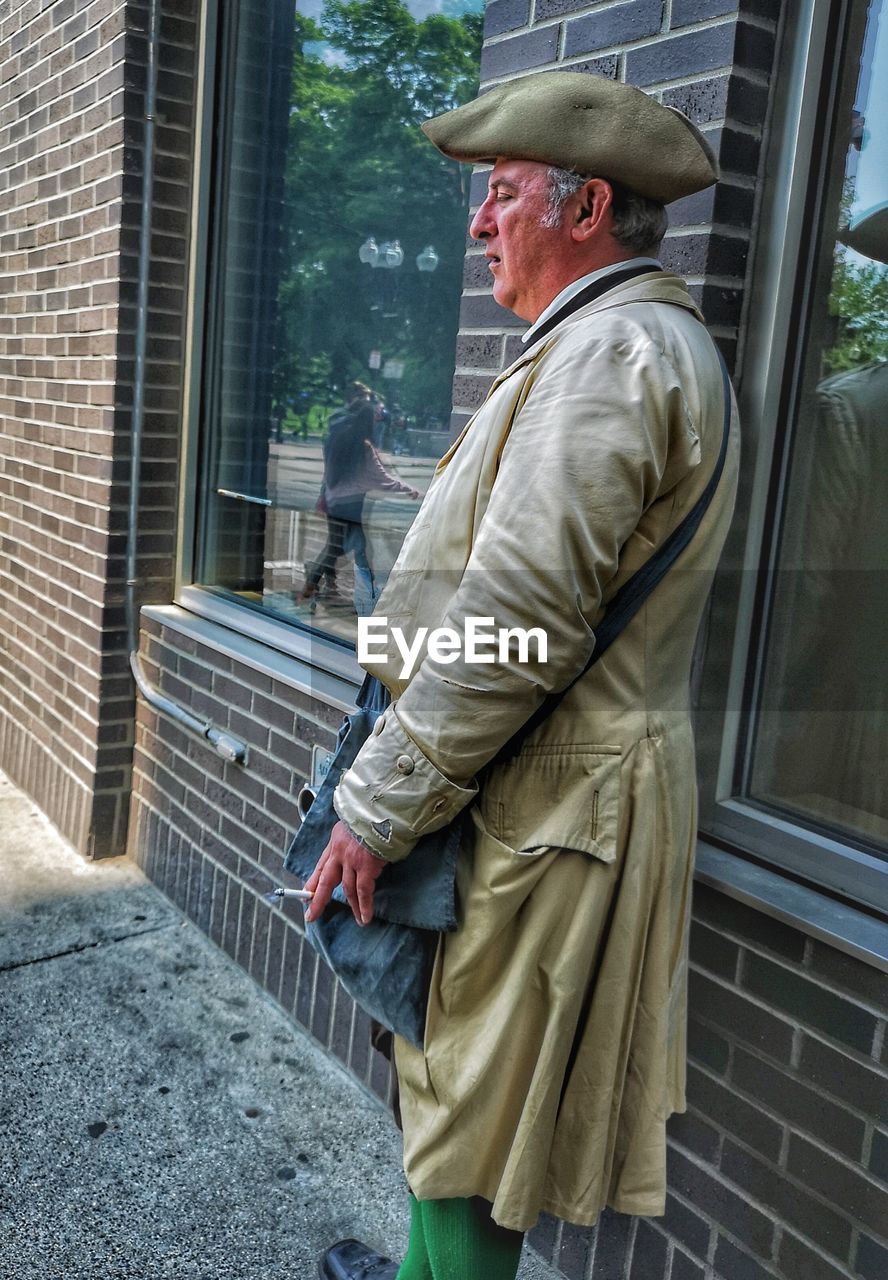 SIDE VIEW OF MAN STANDING WITH UMBRELLA