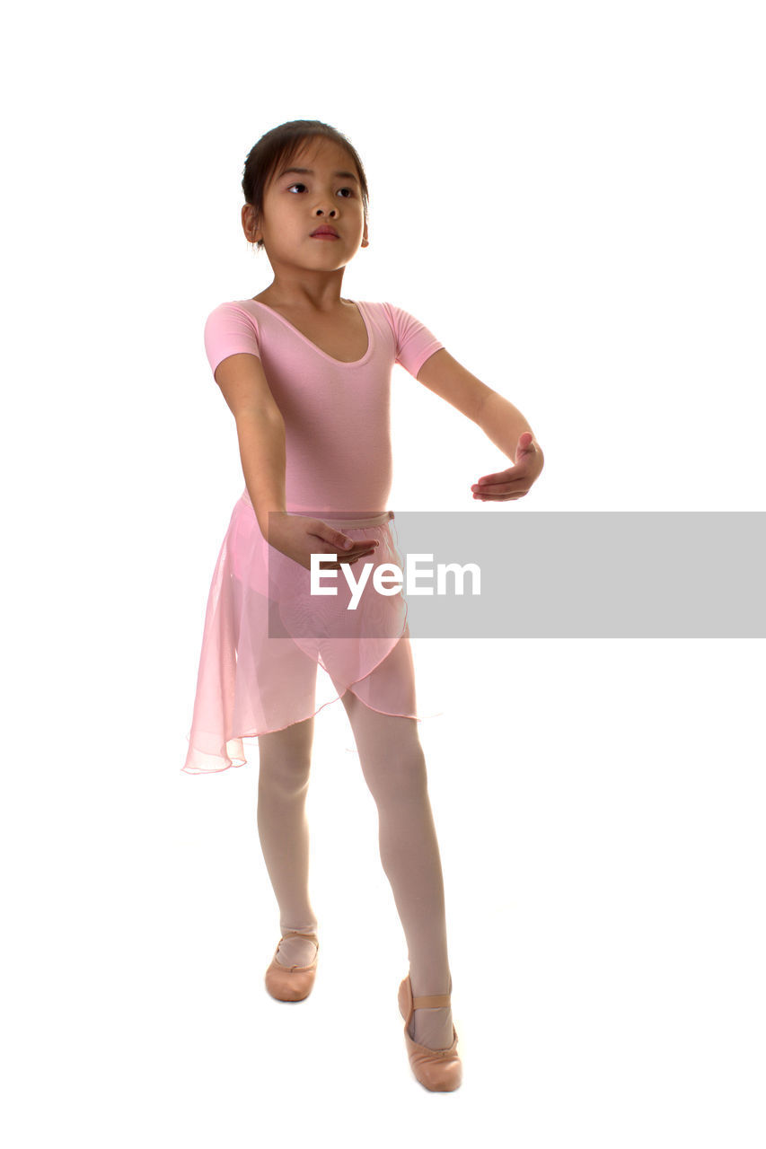 Full length of cute girl dancing against pink background