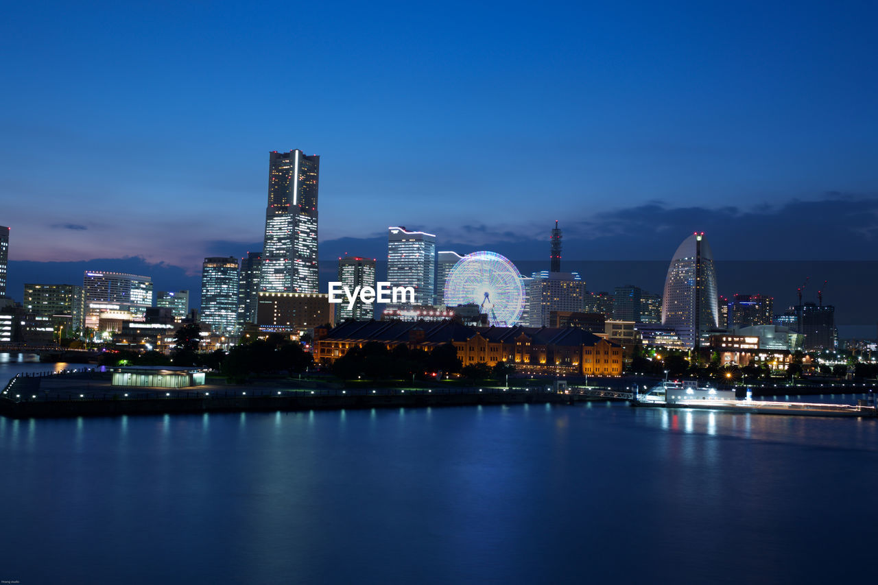 Illuminated cityscape against blue sky