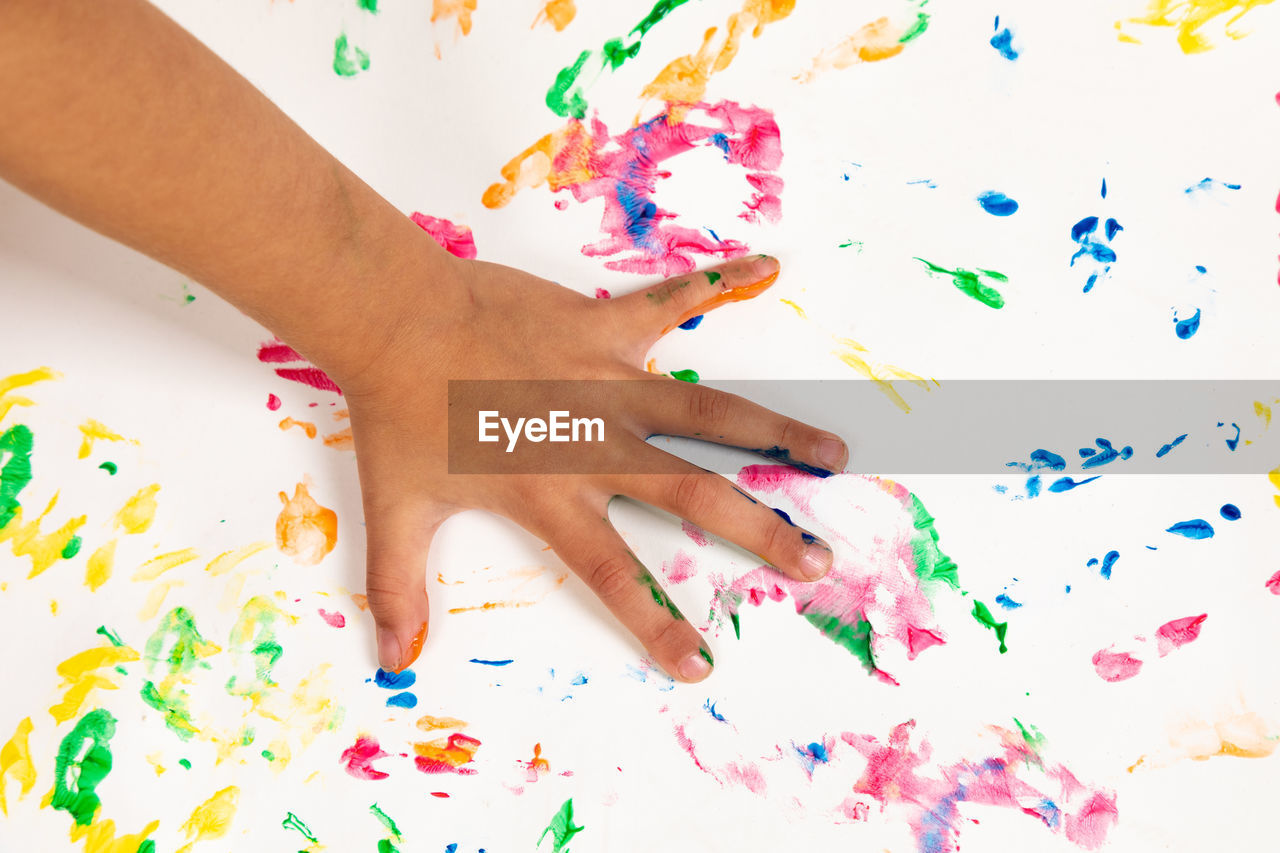 Cropped hand of person touching colorful messy table