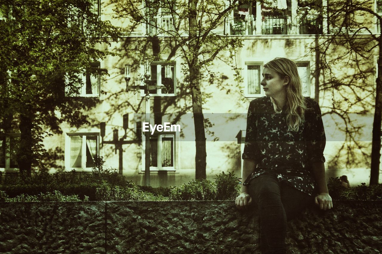 Young woman looking away while sitting in park